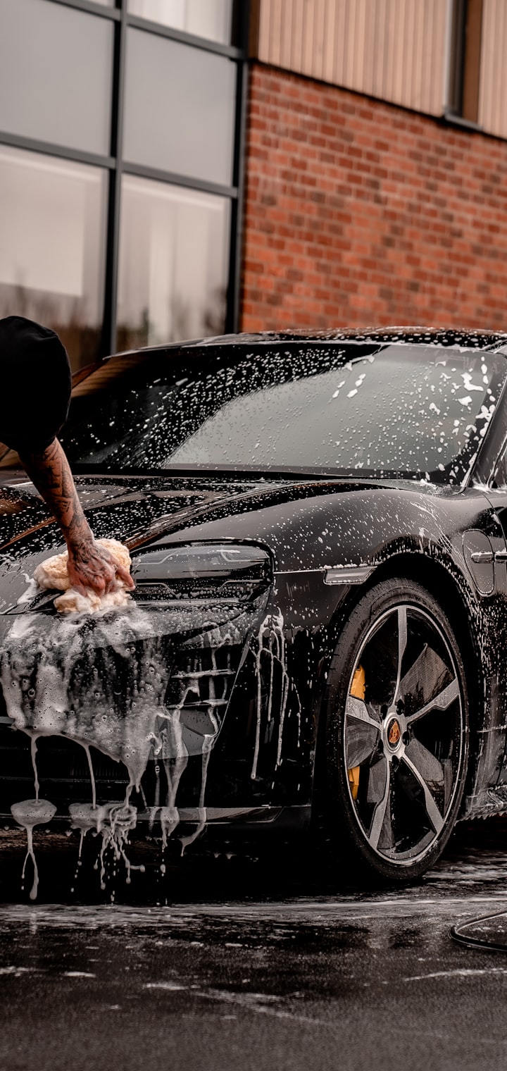 A professional hand-washing a car with foam